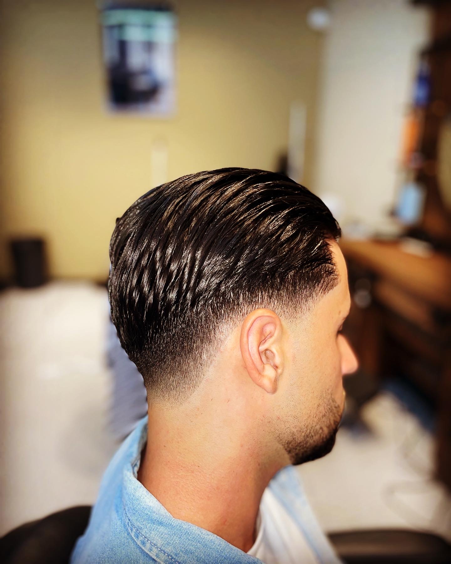 Slick back met een low taper fade, van opzij gezien